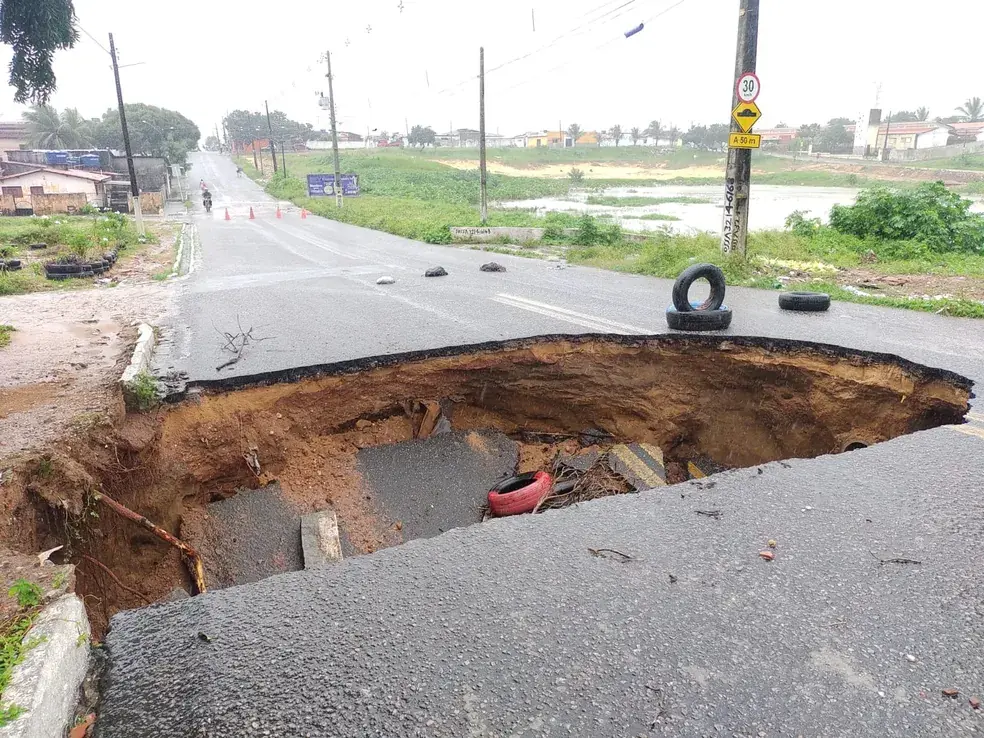 Cratera grande no asfalto, com pneus colocados como aviso